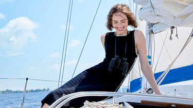 Black sleeveless knit midi dress with white zigzag trim detail, worn on a sailboat.