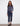 Model wearing dark blue jogger jeans with drawstring waist, paired with a fitted long-sleeve slate blue top and black loafers, standing against white wall