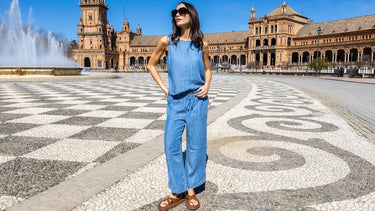 Woman in a chambray sleeveless jumpsuit and sunglasses standing in Plaza de Espaรฑa, Seville.