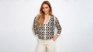 A woman wears a black and off-white crochet cardigan.