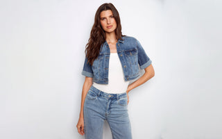 A woman wearing a cropped denim jacket with a white top and light wash jeans.