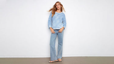 A washed blue pullover sweater paired with light-wash jeans, showing how to style a pullover sweater casually.