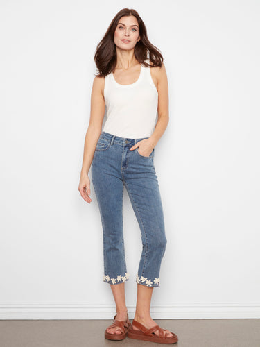 Medium blue jeans with a slim fit and flared leg, featuring floral embroidery at the hem and a classic design by Charlie B.