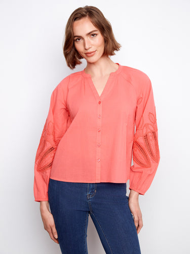 Coral blouse featuring a stand neckline with intricate embroidery on the sleeves, adding a touch of elegance. By Charlie B.