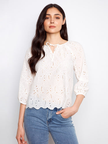 White cotton blouse featuring a notched neckline with tie, eyelet detailing, and scalloped hem by Charlie B.