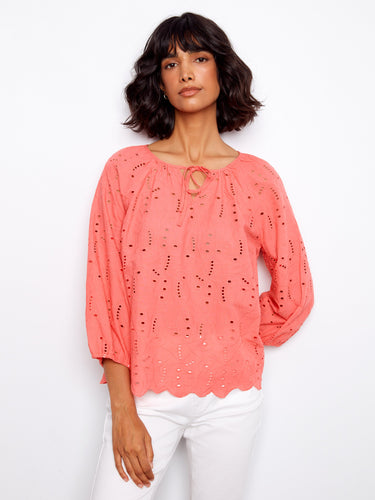Coral blouse featuring a notched neckline with tie, adding a playful touch to the design by Charlie B.