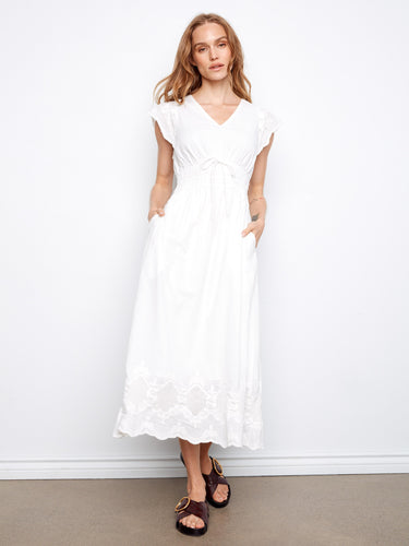 White dress with V-neck and elastic empire waist, featuring hidden pockets for practicality by Charlie B.