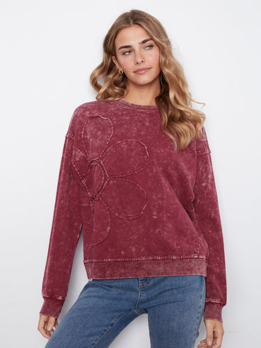 This garment features a floral appliquรฉ detail, adding a touch of elegance to the stretch cotton fabric by Charlie B.