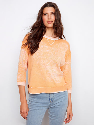 Soft orange top with a crew neckline, featuring a stylish reversed print. Perfect for casual outings. Made by Charlie B.