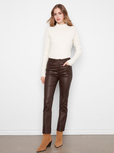 Woman styled in coffee-colored slim leg pants featuring a regular rise, paired with a white top and ankle boots by Charlie B.