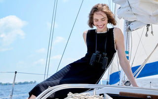  Black sleeveless knit midi dress with white zigzag trim detail, worn on a sailboat.