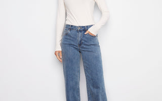 Model wearing wide-leg stretch denim jeans with black boots and a white long-sleeve top.