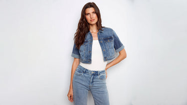 A woman wearing a cropped denim jacket with a white top and light wash jeans.