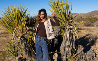 A woman wearing a floral-embroidered vest with jeans in the desert 