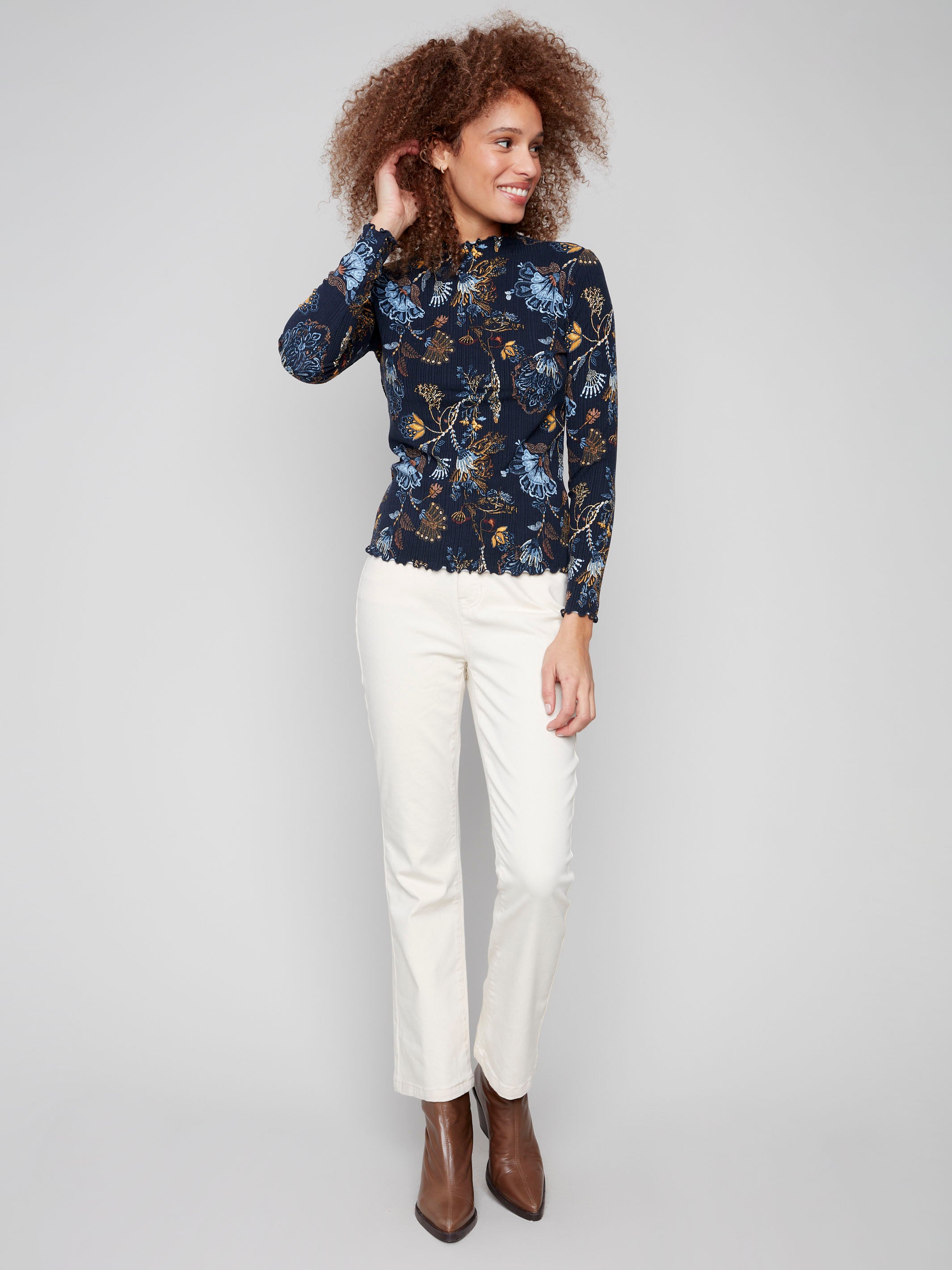 Elegant long-sleeve top showcasing a floral design with ruffle accents at the cuffs, offering a refined look by Charlie B.