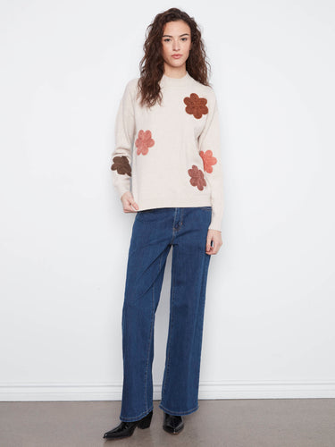 Adorned with intricate floral appliqué embroidery, this sweater brings a playful elegance to any wardrobe by Charlie B.
