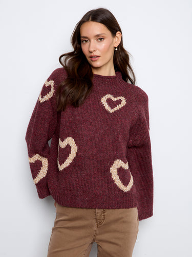 This lovely knit piece boasts a mock neck and playful heart details, offering warmth and style in equal measure for cooler days by Charlie B.
