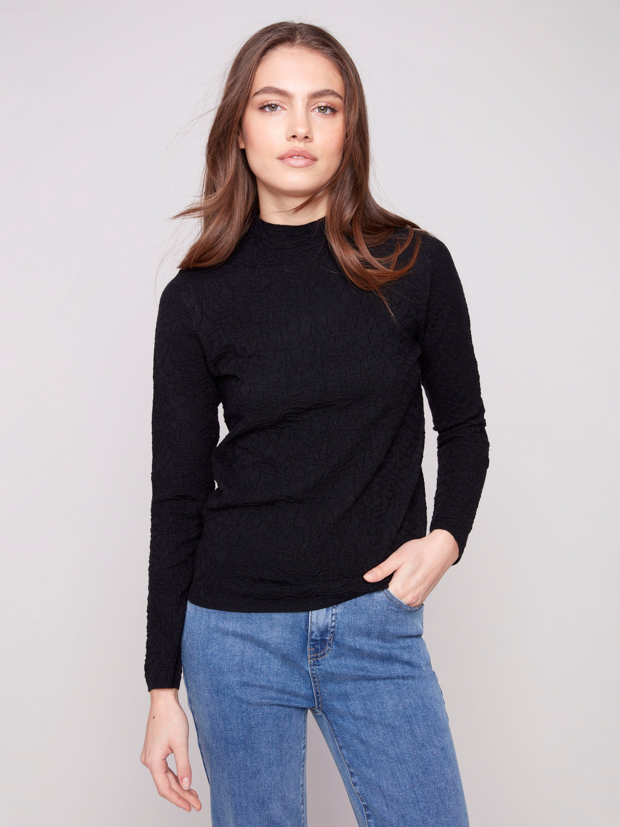 Elegant black sweater with a chic mock neck, paired with casual blue jeans for a stylish look by Charlie B.