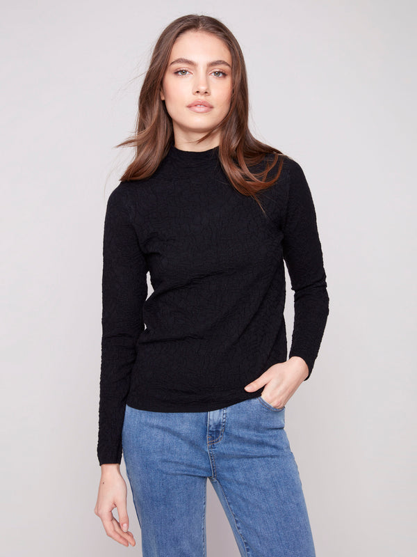 Elegant black sweater with a chic mock neck, paired with casual blue jeans for a stylish look by Charlie B.