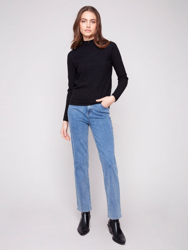 Stylish ensemble showcasing a slim fit black sweater and blue jeans, creating a sleek silhouette by Charlie B.