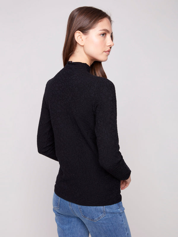 Chic black textured sweater styled effortlessly with classic blue jeans for modern elegance by Charlie B.
