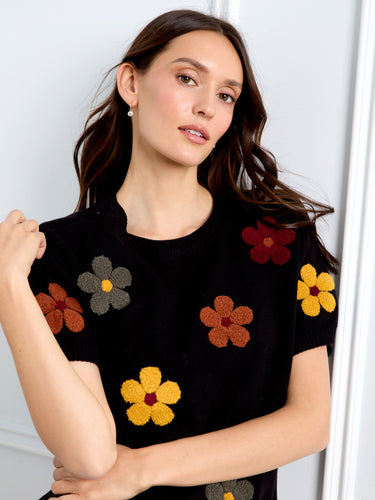Elbow-length sleeves on a black sweater adorned with colorful flowers by Charlie B.