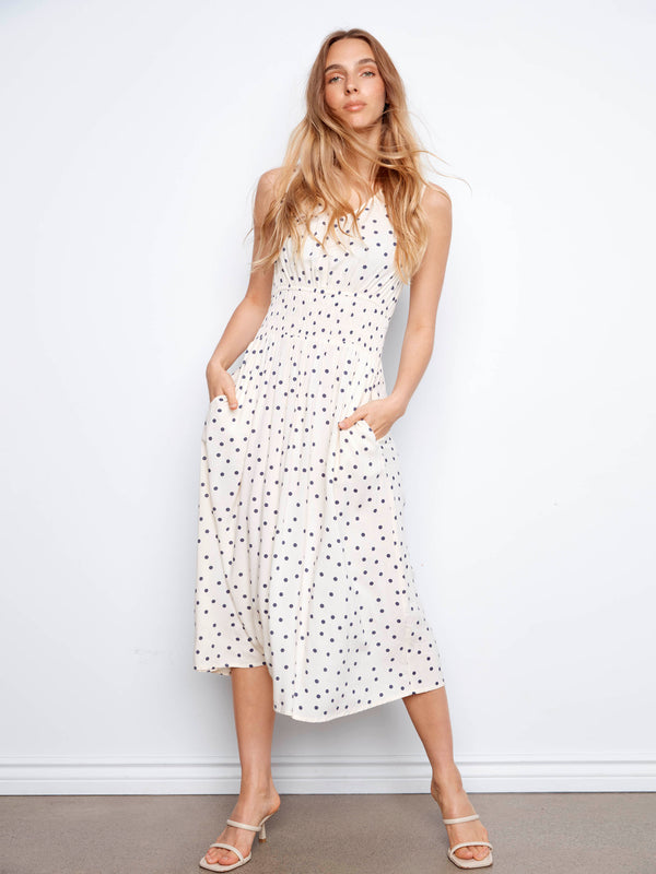 Chic sleeveless dress in white with black polka dots, featuring a stylish smocked waist by Charlie B.