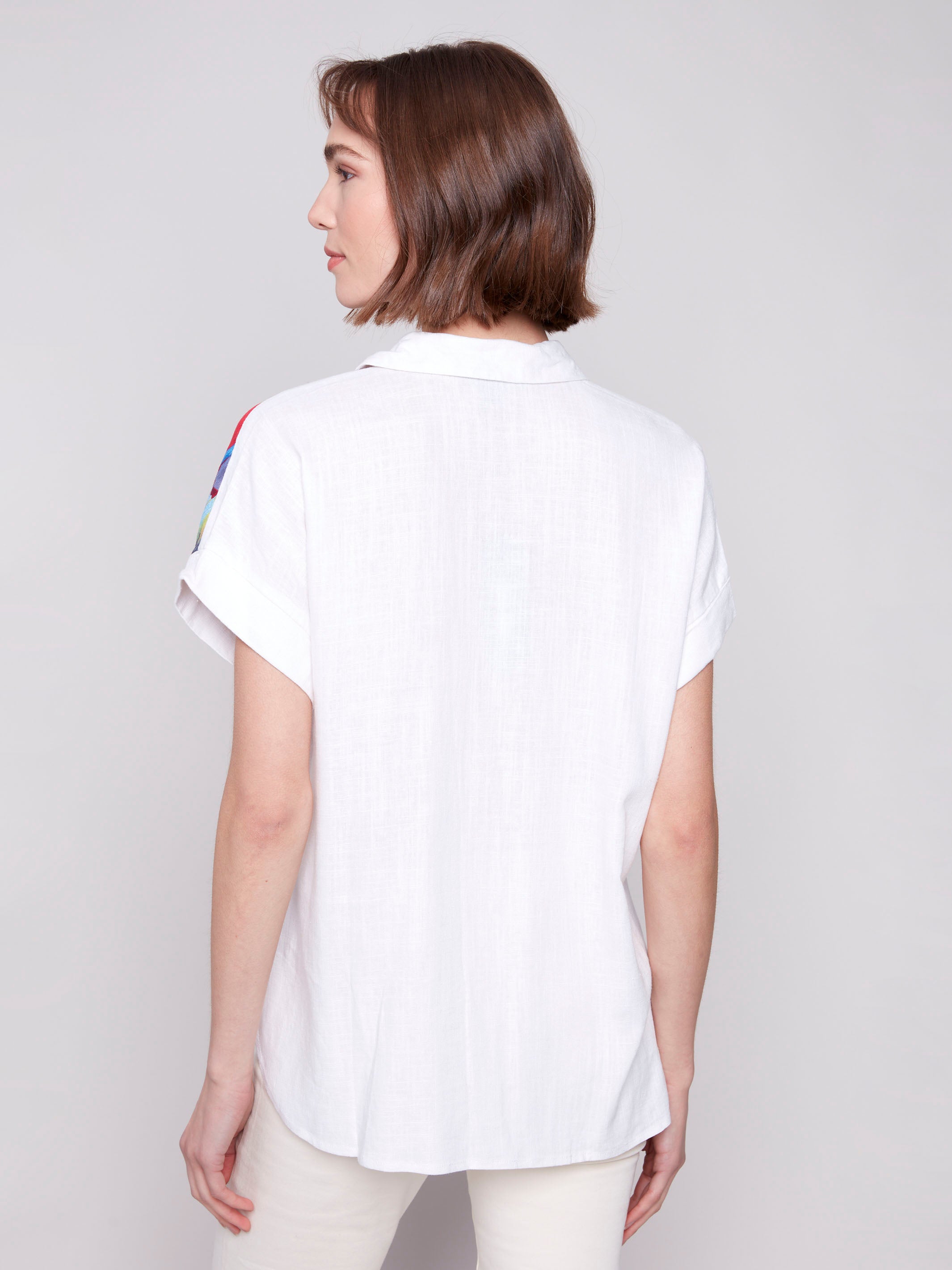 White shirt featuring one shoulder feather design by Charlie B.
