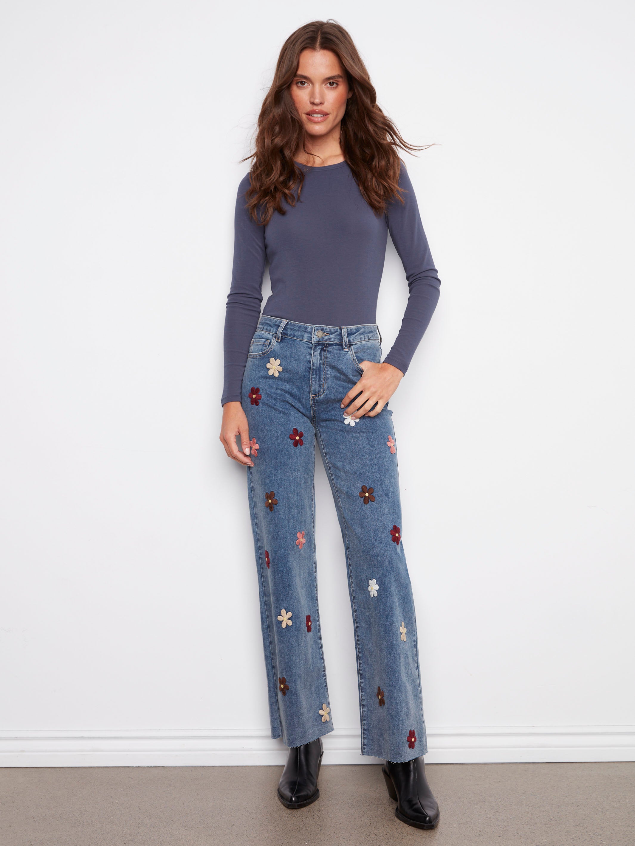 Medium blue jeans with a stylish raw hem and vibrant flower patches, offering a trendy look by Charlie B.