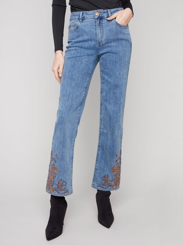 These jeans feature intricate lace embroidery at the hem, adding a touch of elegance to the stretch denim fabric by Charlie B.