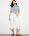 White pants with a flared leg, featuring intricate lace hem detail for added elegance. Crafted from stretch twill fabric by Charlie B.