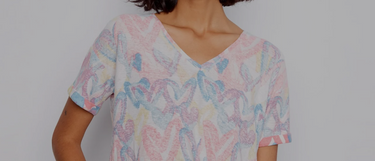 A woman wearing a V-neck top outfit in a pastel heart print with short sleeves, paired with white straight-leg pants.