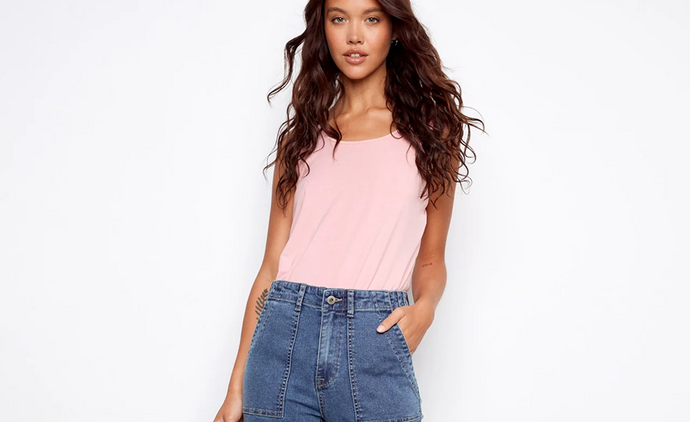  A woman wearing mid-wash wide-leg cropped jeans with patch pockets and a pink tank top.