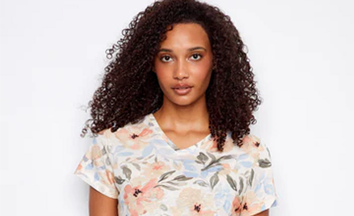 Woman in a short-sleeve women’s linen shirt featuring a soft watercolor floral print and dark jeans.