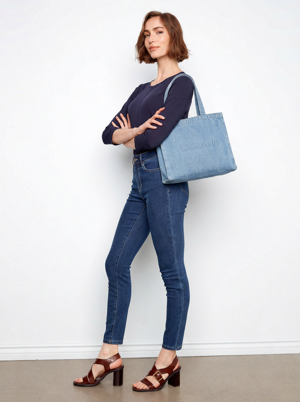 This denim tote bag offers a spacious interior pocket, perfect for organizing essentials, along with a stylish logo by Charlie B.
