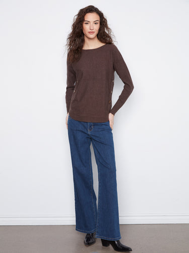 Model wearing a cozy brown sweater showcasing ribbed sleeves, adding elegance to the casual ensemble of jeans by Charlie B.