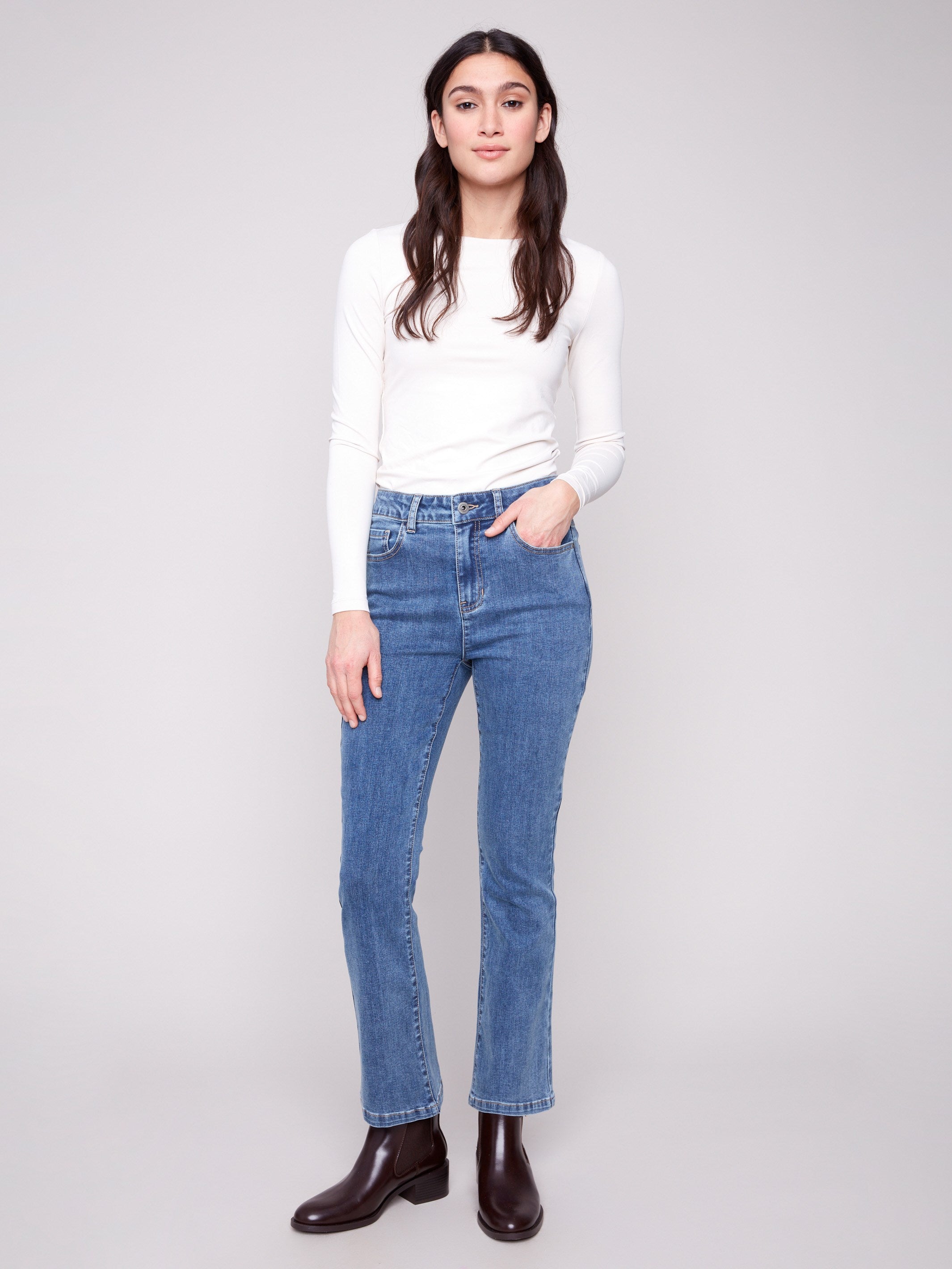 Medium blue bootcut denim pants by Charlie B featuring a stylish mid-rise waist, perfect for everyday wear.