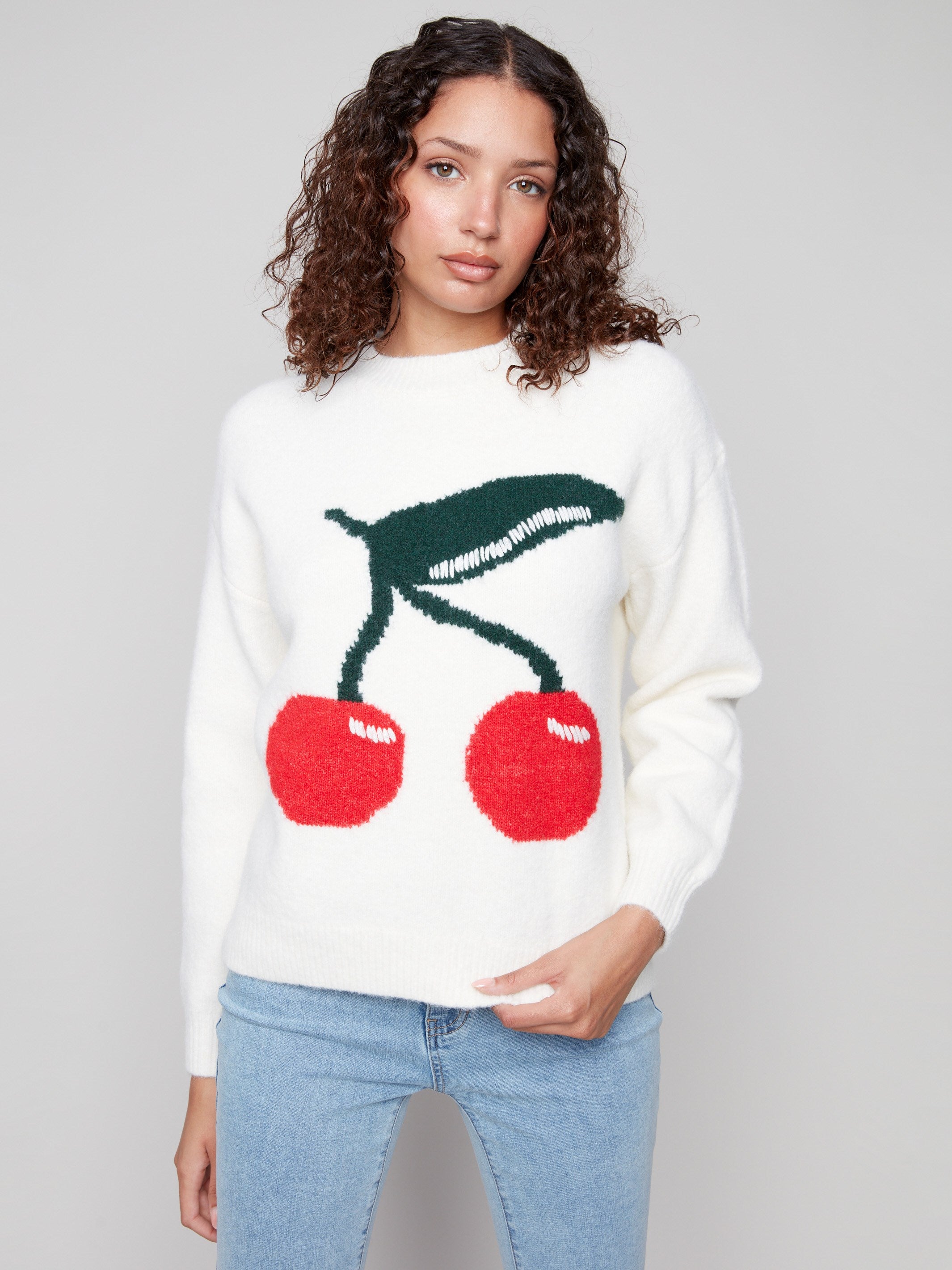 White intarsia sweater with a plush texture and vibrant cherry design by Charlie B.