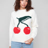 White intarsia sweater with a plush texture and vibrant cherry design by Charlie B.