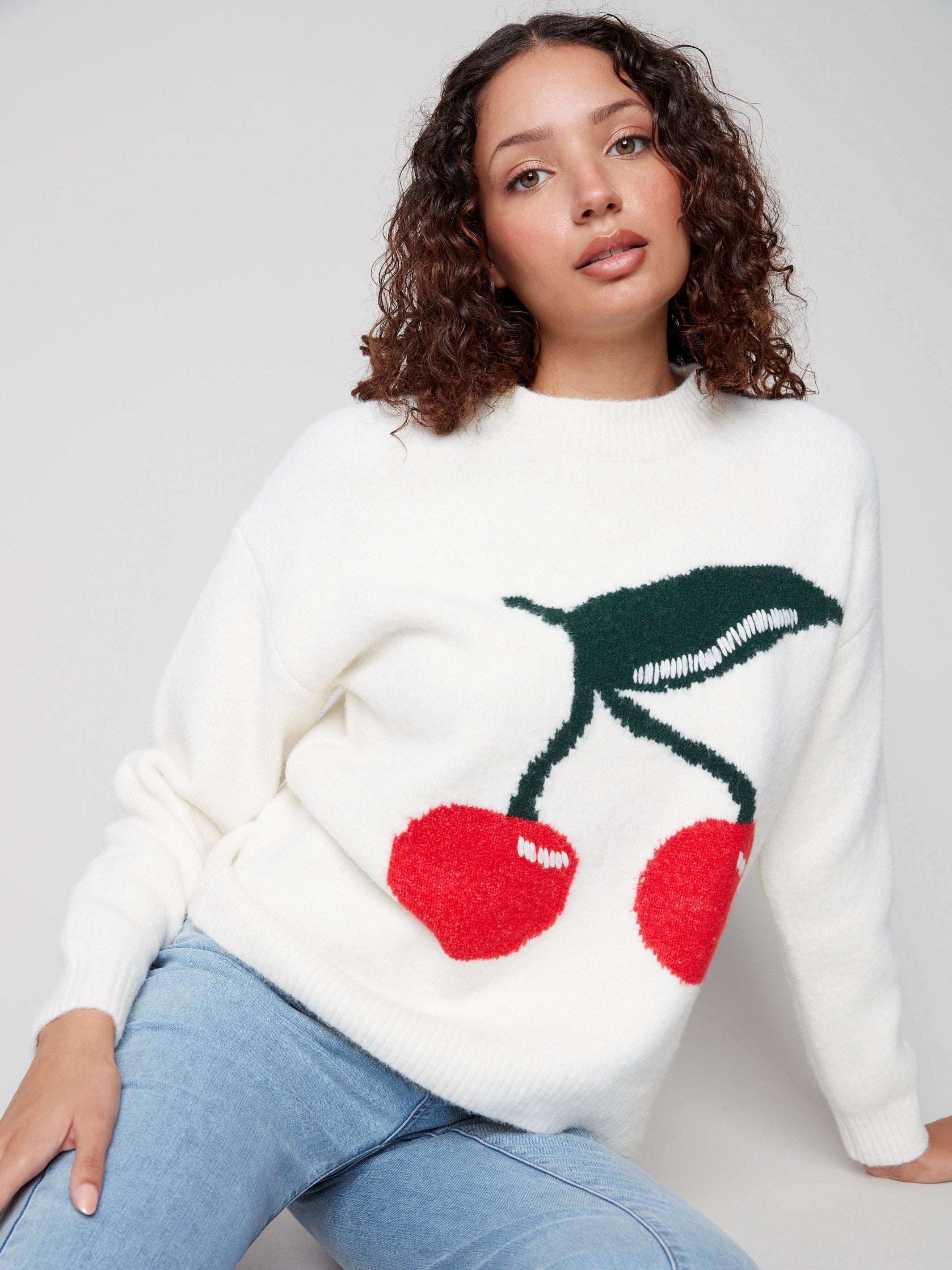 White sweater featuring a vivid cherry pattern and cozy drop shoulders by Charlie B.