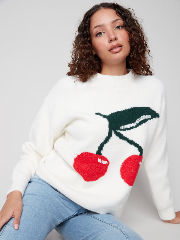 White sweater featuring a vivid cherry pattern and cozy drop shoulders by Charlie B.