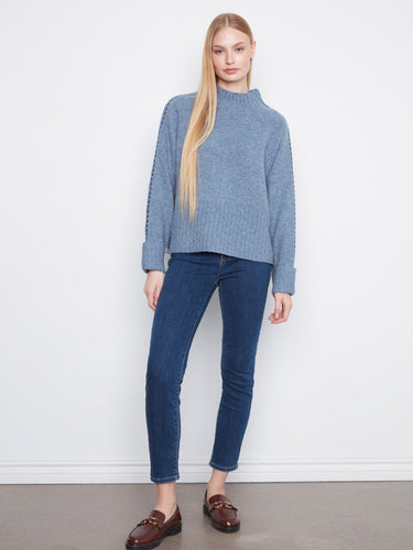 Stylish blue sweater showcasing contrast stitching details along the sleeves, offering a chic look by Charlie B.
