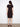 Chic black dress showcasing unique design elements like the waist tie and cuffed sleeves for added flair by Charlie B.