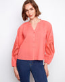 Coral blouse featuring a stand neckline with intricate embroidery on the sleeves, adding a touch of elegance. By Charlie B.