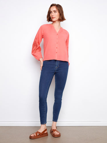 Chic coral blouse with button-front closure and delicate sleeve embroidery for a stylish look. By Charlie B.