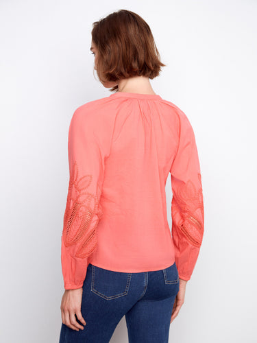 Coral top with unique sleeve embroidery, offering both style and comfort in its design. By Charlie B.