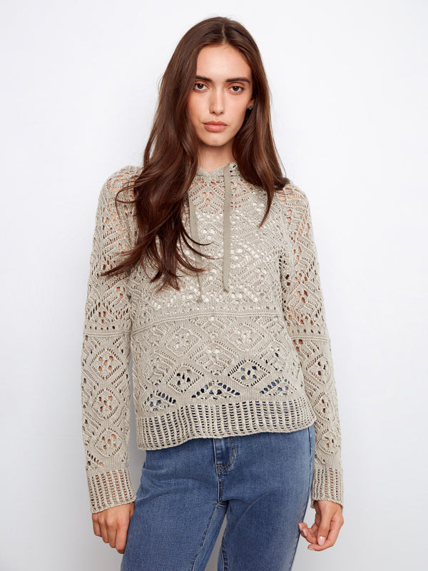 The sweater features a hooded design, adding a cozy touch to its intricate knit pattern. Perfect for casual outings. By Charlie B.