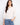 White cotton blouse featuring a notched neckline with tie, eyelet detailing, and scalloped hem by Charlie B.