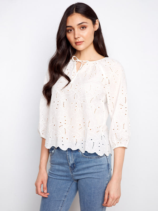 Chic white blouse showcasing delicate eyelet detailing and a stylish scalloped hem for a feminine touch by Charlie B.