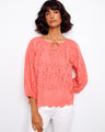 Coral blouse featuring a notched neckline with tie, adding a playful touch to the design by Charlie B.